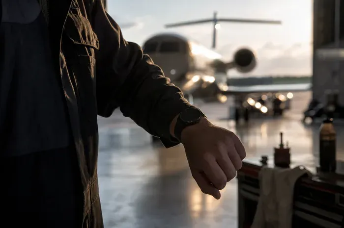 A wrist watch checked against a waiting jet on the ramp