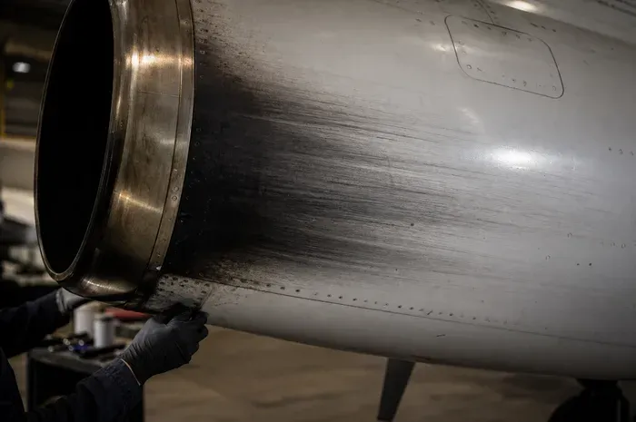 Jet exhaust soot streaked back across white fuselage paint