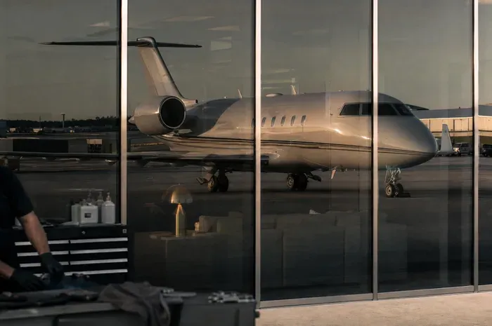 A business jet mirrored in the glass frontage of an FBO terminal