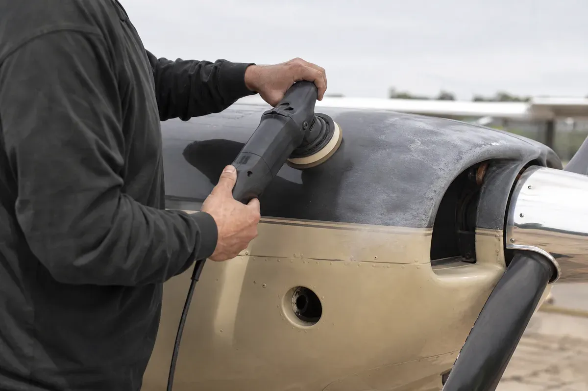 A polisher correcting oxidation on the cowling of a single-engine aircraft