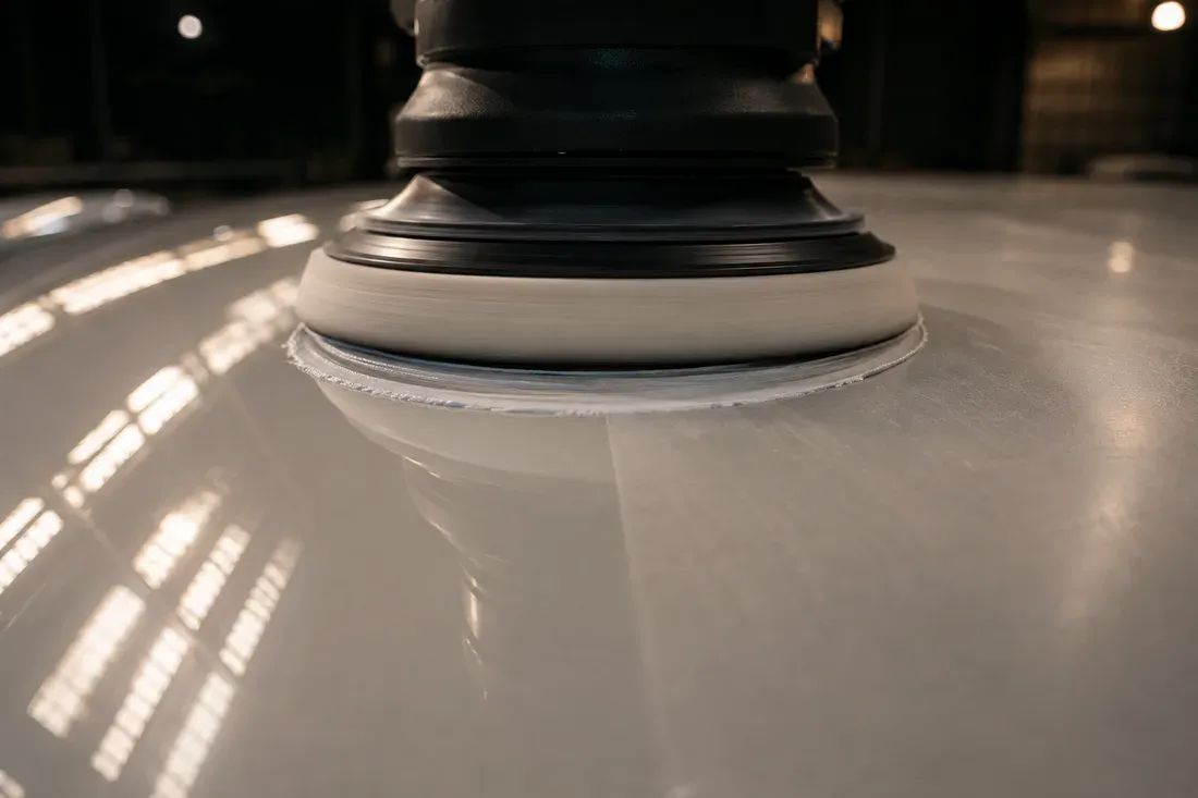 Macro view of a polisher's foam pad against a glossy white aircraft panel