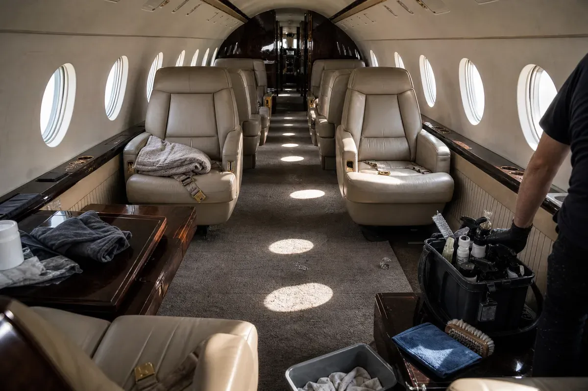 A private jet cabin before detailing, seats disordered and seatbelts loose