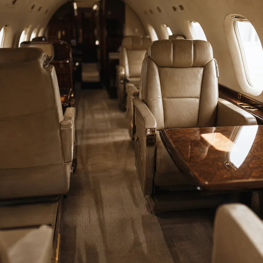 A private jet cabin after detailing, with cream leather club seats and a polished burl wood table