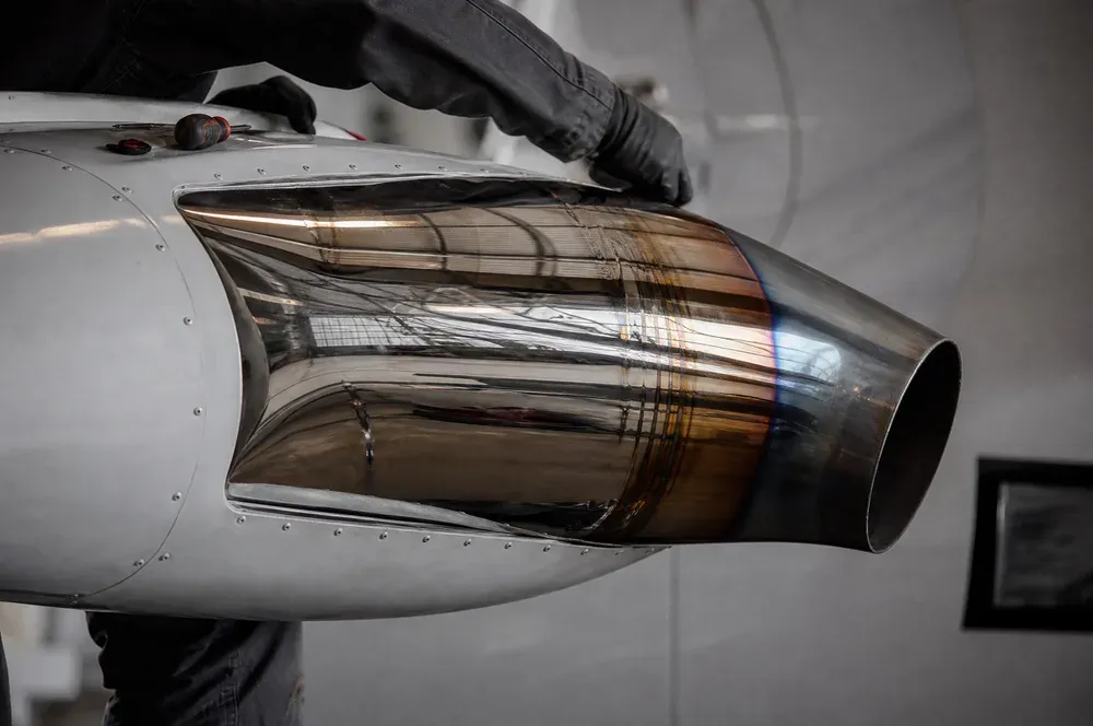 A mirror-polished stainless exhaust stack with heat tint still visible under the finish